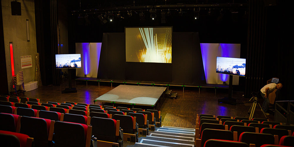 Projection screens and seats in empty conference auditorium
